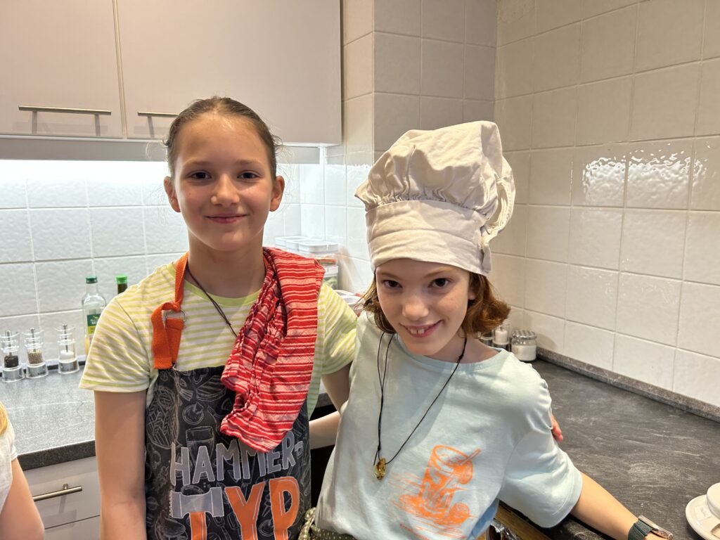 Schülerinnen in der Küche, eine mit Kochmütze