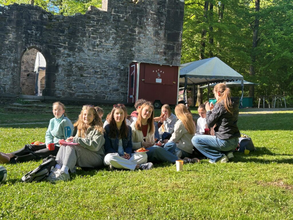 Gruppe Schüler beim Picknick auf der Wiese vor St. Barbara Ruine