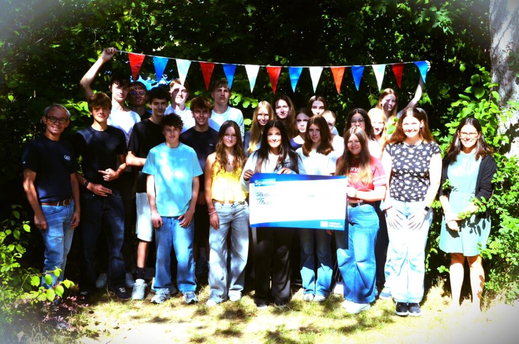 Gruppenbild Schüler mit Fähnchengirlande im Schattenlichtspiel der Bäume
