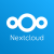 Das Bild zeigt das Logo von Nextcloud auf einem blauen Hintergrund. Das Logo besteht aus drei kreisförmigen Elementen: zwei größere, weiße Kreise auf der linken und rechten Seite und ein kleinerer, ausgefüllter Kreis in der Mitte. Unter den Kreisen steht der Schriftzug "Nextcloud" in weißer Schrift. Die Gestaltung ist einfach und modern, was auf eine benutzerfreundliche Cloud-Lösung hinweist.